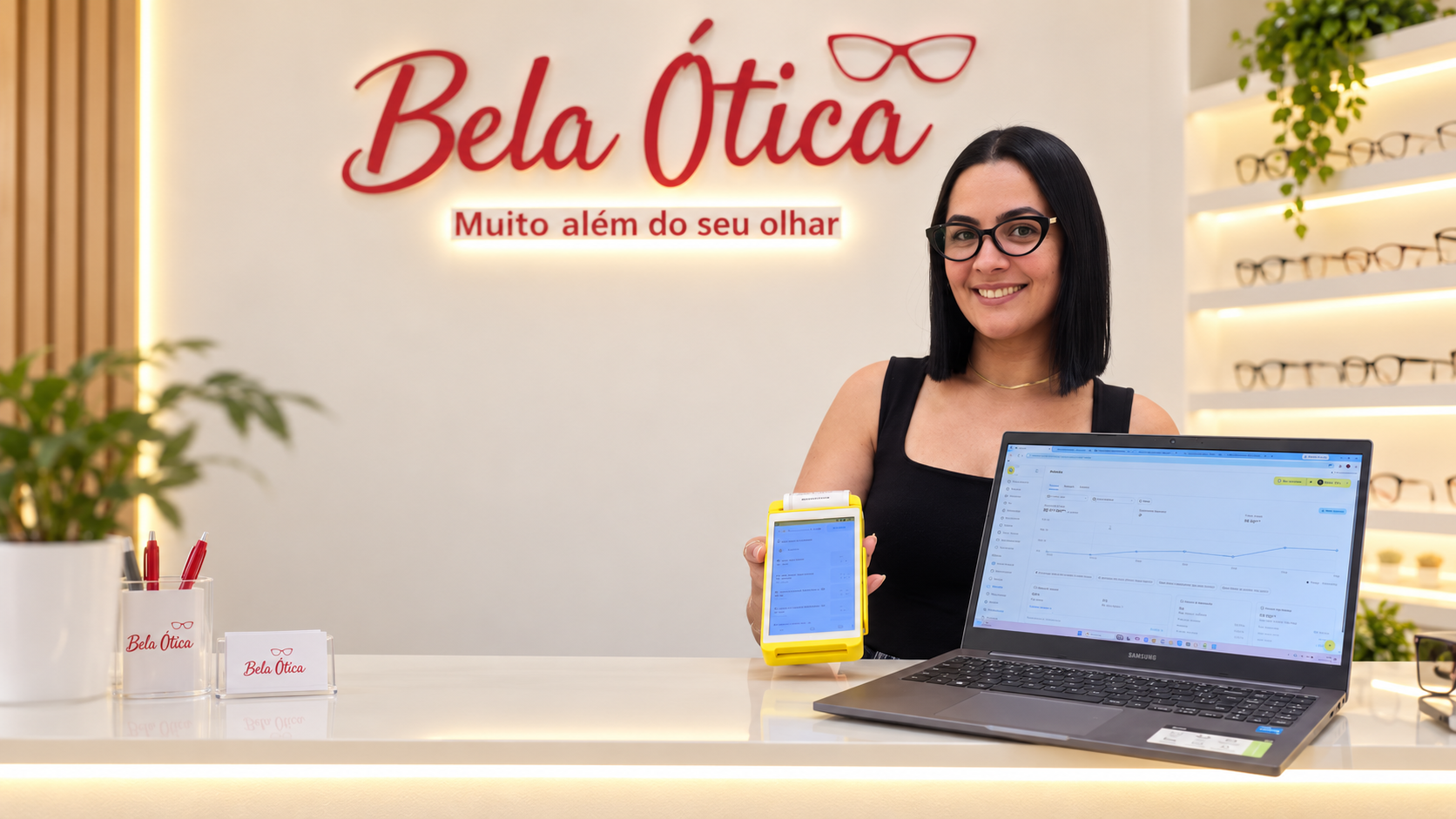 Lojista da Bela Ótica no balcão usando a maquininha e o Sistema de Gestão no notebook